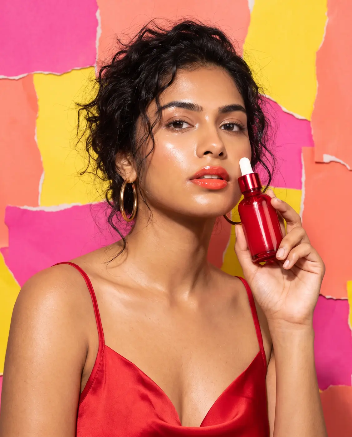 Model holding a red serum bottle against pink and yellow torn paper